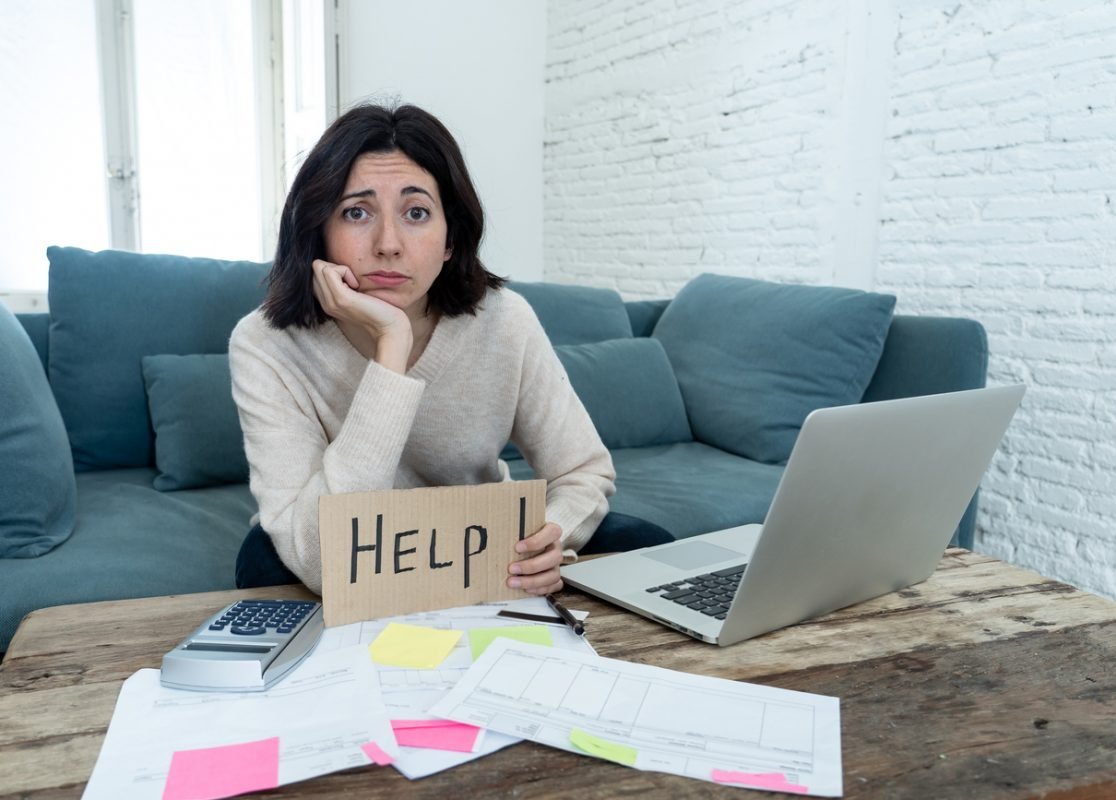 Portrait of worried young woman feeling stressed and desperate asking for help in paying bills, debts, tax expenses and accounting home finances with laptop. In online banking and financial problems.